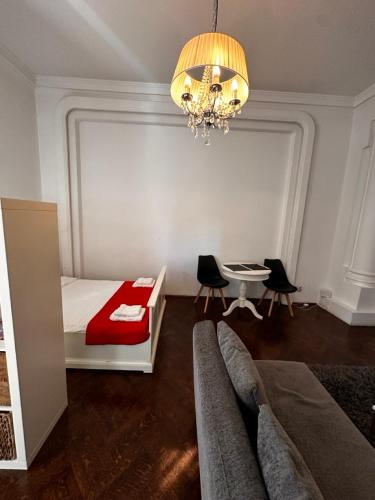 a bedroom with a bed and a table and a chandelier at Cismigiu Apartments in Bucharest