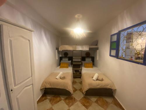 a small room with two beds in a room at Nizar Surf Morocco in Taghazout
