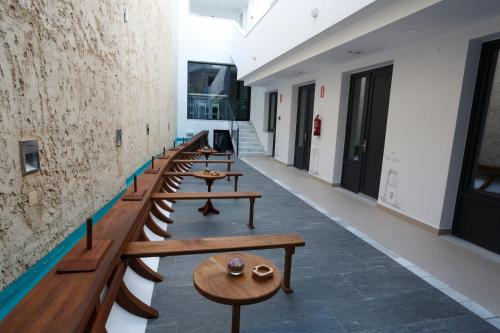 una fila de bancos de madera en un pasillo en La Pasajera Hostal Boutique, en Conil de la Frontera