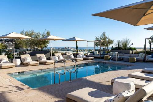 a swimming pool with lounge chairs and umbrellas at The Pearl Coast - Rooftop Pool, Gym Luxurious 2BR Santa Monica in Los Angeles