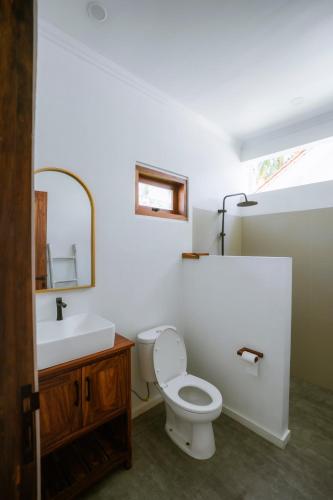 a bathroom with a toilet and a sink and a mirror at Rumah Markisa Batukaras in Batukaras