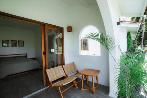 a bedroom with a bed and a table and a chair at Rumah Markisa Batukaras in Batukaras