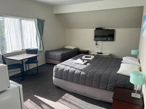 a hotel room with a bed and a table and a desk at Drury Motor Lodge in Drury