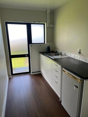 a kitchen with white cabinets and a large window at Drury Motor Lodge in Drury