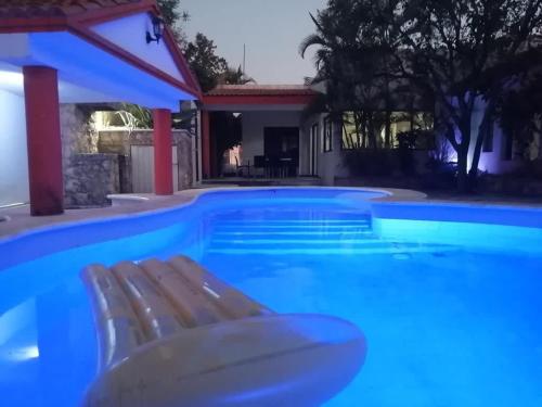 a blue swimming pool with a bench and a house at Increible Loft con piscina 3 personas Casa Montes in Mérida