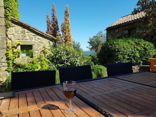 a glass of wine sitting on a wooden table at La Patouille Comfortable holiday residence in Aujac
