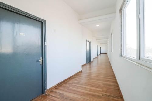 ein leerer Flur mit einer Tür und Fenstern in der Unterkunft Townhall in Bhiwadi
