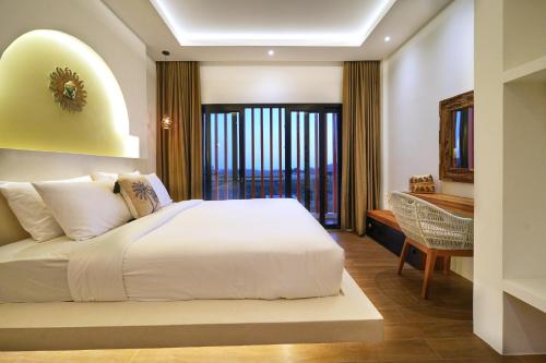 a bedroom with a large white bed and a desk at Kamalie Bali Luxury in Tanah Lot