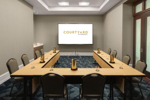 a conference room with tables and chairs and a screen at Courtyard by Marriott Chicago at Medical District-UIC in Chicago