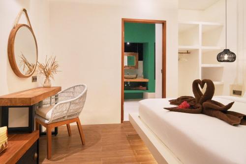 a bedroom with a bed and a desk and a mirror at Kamalie Bali Luxury in Tanah Lot