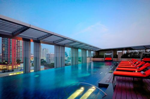 a pool on the roof of a building with red chairs at Bangkok Marriott Hotel Sukhumvit in Bangkok