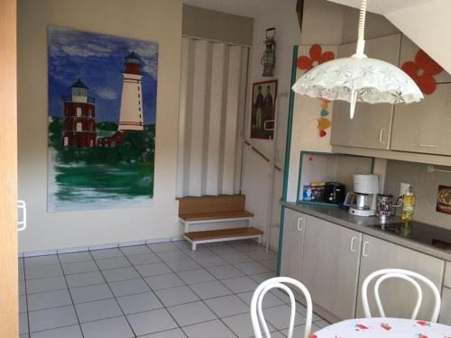a kitchen with a table and a lighthouse painting on the wall at Lobbe mit direkter Strandlage in Middelhagen