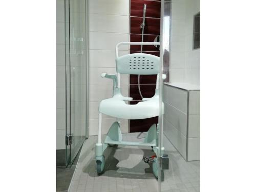 a white chair in a bathroom next to a shower at "Annelies" - barrier-free in Neufriedersdorf