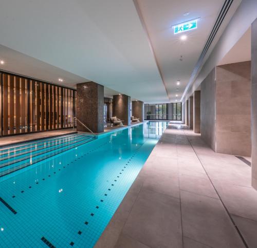 an indoor swimming pool with blue water in a building at Melbourne Corporate Stays - Docklands Waterfront in Melbourne