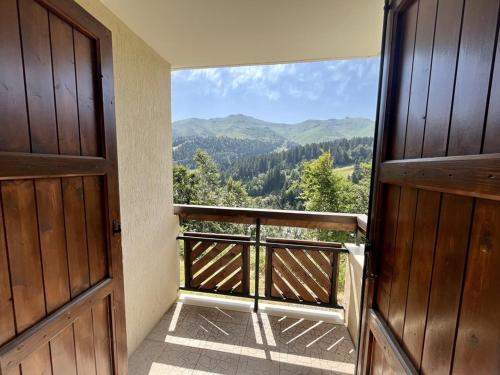 Une porte ouverte s'ouvre sur un balcon offrant une vue sur les montagnes. dans l'établissement Charmant T2 proche pistes avec parking et balcon - FR-1-787-79, à Laveissière
