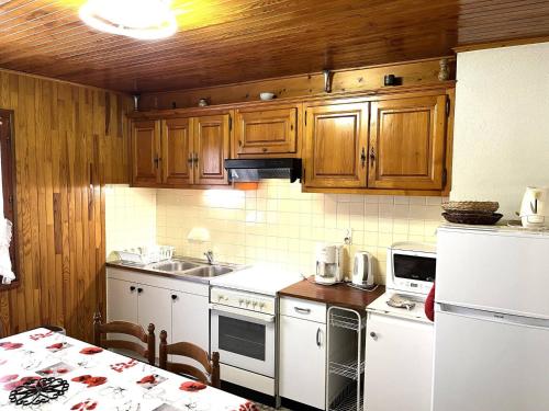 une cuisine avec des appareils électroménagers blancs et des armoires en bois dans l'établissement Appartement 60 m² à Autrans, confort & animaux acceptés - FR-1-737-85, à Autrans