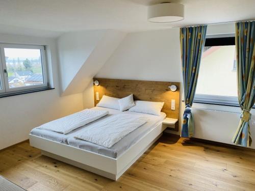 Un dormitorio con una cama blanca y dos ventanas. en Apartment Annemarie 1, en Meersburg
