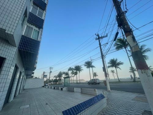 Cantinho à beira mar في برايا جراندي: مبنى وشارع مع أشجار النخيل وسيارة