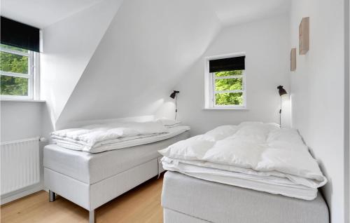 two beds in a white room with two windows at Four-Bedroom Holiday Home In Juelsminde in Juelsminde