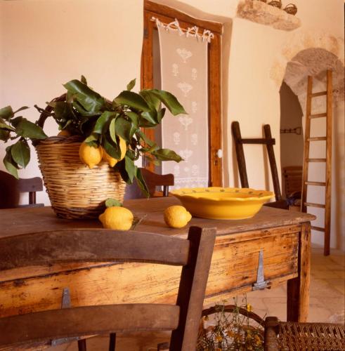 a table with a potted plant and a basket of lemons at I Trulli Di Acquarossa in Cisternino