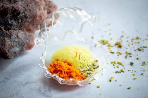 a glass container filled with orange ingrediants on a table at JW Marriott Marquis Hotel Dubai in Dubai