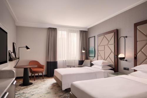 a hotel room with two beds and a desk at Sheraton Istanbul Levent in Istanbul