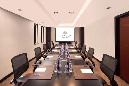 a conference room with a long table with chairs and a screen at Sheraton Istanbul Levent in Istanbul