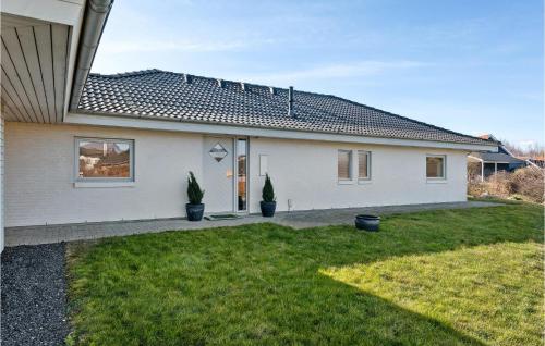 a white house with two potted plants in the yard at Awesome Home In Skårup Fyn With 4 Bedrooms in Oure