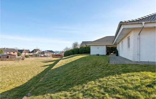 a large grassy yard next to a white house at Awesome Home In Skårup Fyn With 4 Bedrooms in Oure