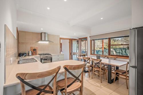 eine Küche mit einer Theke, einem Tisch und Stühlen in der Unterkunft Porepunkah Cottage in Porepunkah