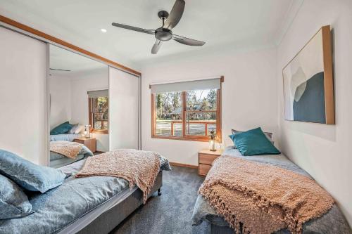 a bedroom with two beds and a ceiling fan at Porepunkah Cottage in Porepunkah