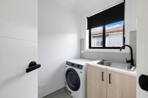 a kitchen with a washing machine and a sink at Cottage Myrtleford in Myrtleford