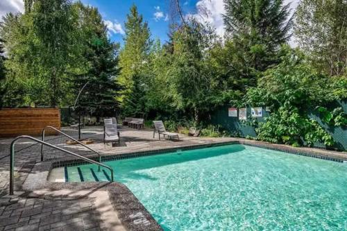 a swimming pool in a yard with chairs and trees at Powder & Pines Boutique Apartment in Whistler
