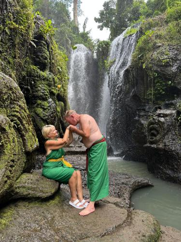 a man and woman in front of a waterfall at Kamalie Bali Luxury in Tanah Lot