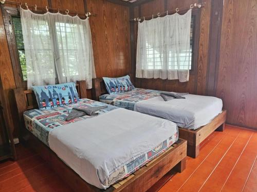 two beds in a room with wooden walls and windows at Tao Thong Villa 2 in Ko Tao