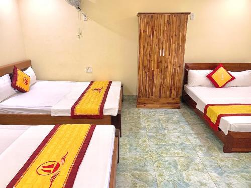 a room with two beds and a wooden cabinet at Huong Cang Sea View Hotel in Cat Ba