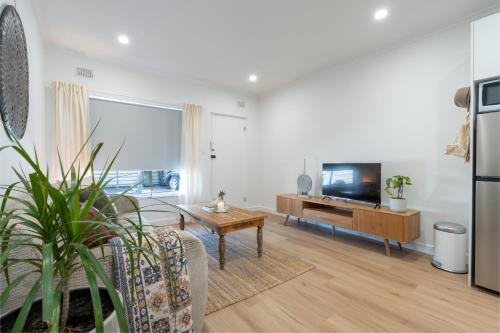 a living room with a couch and a tv at Little Kintore City Escape in Thebarton