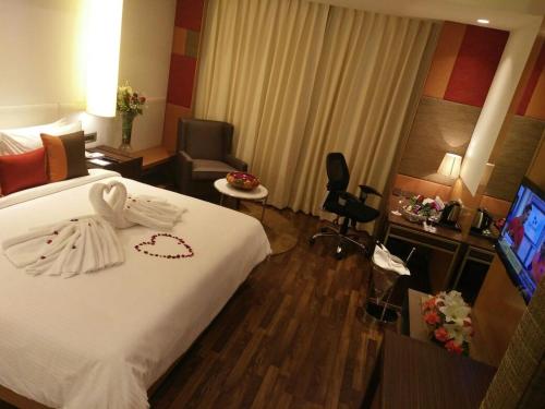 a hotel room with a bed with a swan on it at Deventure Sarovar Portico Kapashera, New Delhi in New Delhi