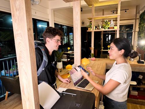 a man and a woman standing at a table with a laptop at Bangkok Neighborhood Hostel in Bangkok