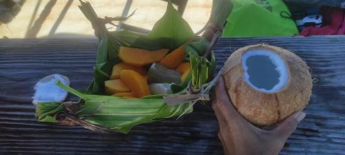 a person holding a coconut with a bunch of fruit at Penu Maurua 1 in Te-Fare-Arii