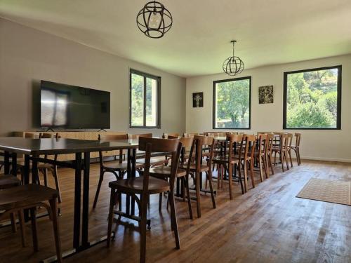 a dining room with tables and chairs and a flat screen tv at Maison Vidal, au pied de l'Aubrac in Coubisou