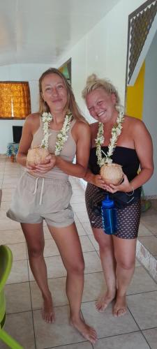 two women standing next to each other holding food at Penu Maurua 1 in Te-Fare-Arii