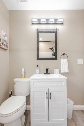 a white bathroom with a toilet and a mirror at Bourbon Trail Bungalow in Lebanon