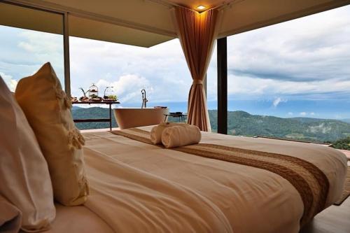 a large bed in a room with a large window at La Villa Hill-ลาวิลล่าฮิลล์ in Mon Jam