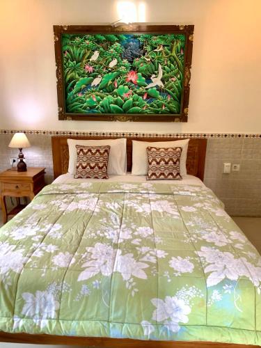 a bedroom with a bed with a painting on the wall at Bagus Homestay in Ubud