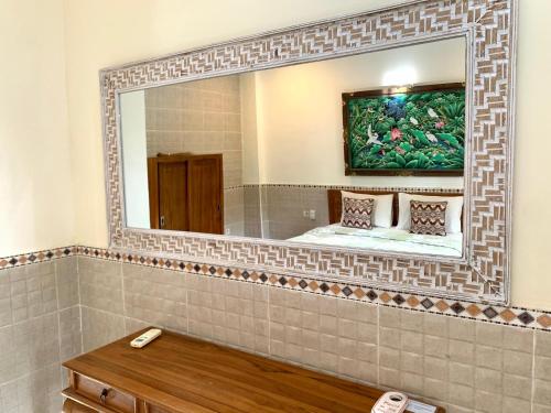 a bathroom with a mirror and a bed in it at Bagus Homestay in Ubud