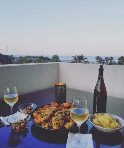 une table avec une assiette de nourriture et deux verres de vin dans l'établissement 2 pièces magnifique vue mer et montagne, à Bastia