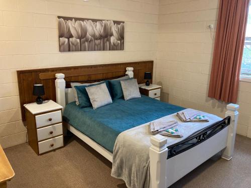 a bedroom with a bed and two nightstanduments sidx sidx sidx sidx at Flinders Ranges Motel - The Mill in Quorn