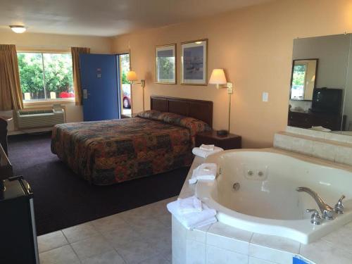 um quarto de hotel com uma banheira e uma cama em Belmont Inn and Suites em Hampton
