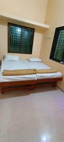 a bedroom with two beds and two windows at Mallikarjun Residency with AC in Akalkot